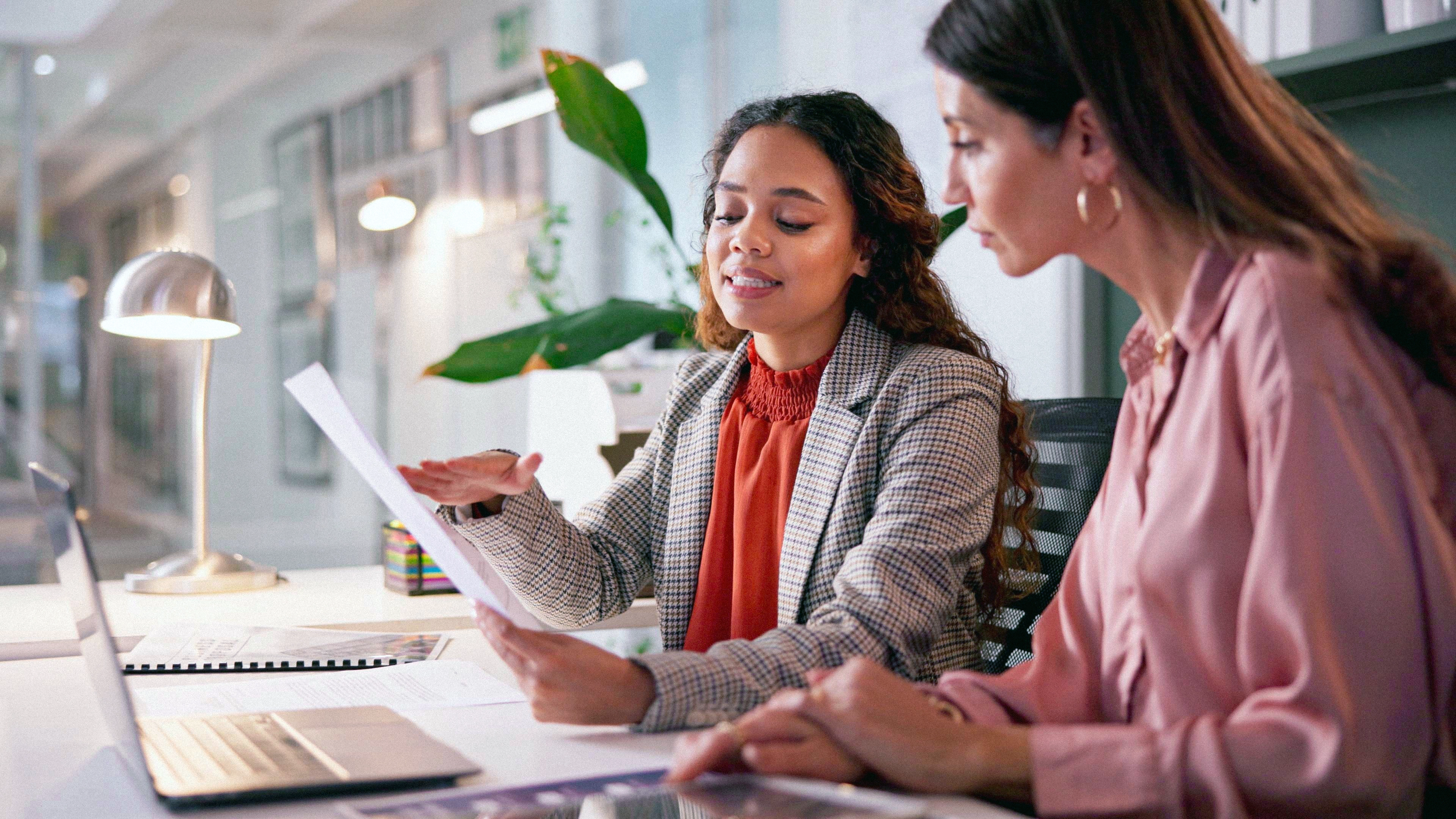 Two people working together over documents in a bright office